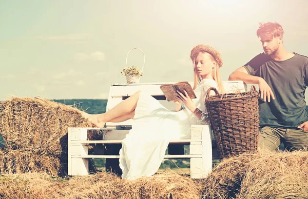 Familia disfrutar de la naturaleza de verano. Mujer novia en vestido de novia relajarse en el banco. Mujer sensual leer libro para el hombre. Pareja enamorada de vacaciones. Novia y novio fecha al aire libre — Foto de Stock