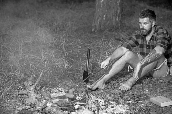 ひげロースト ソーセージに火で流行に敏感。焚き火に男の料理食品のひげを生やした。格子縞のシャツの男は自然でリラックスします。観光では、キャンプをお楽しみください。夏の休暇の概念。キャンプや調理食品、ヴィンテージ — ストック写真