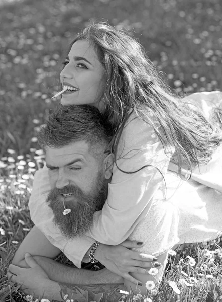 Hombre y mujer acostados en la hierba el día de primavera. Pareja en caras sonrientes fumando al aire libre, naturaleza en el fondo. Pareja enamorada pasar tiempo al aire libre y fumar. Concepto de hábito de fumar . — Foto de Stock