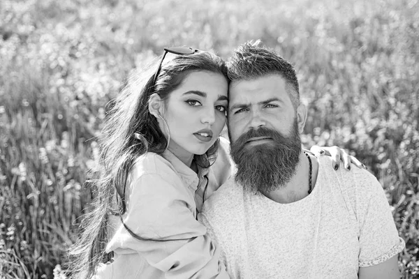 Мужчина с бородой и женщина сидят в травяной весенний день. Весенний отдых. Влюбленные проводят время на свежем воздухе и обнимаются. Пара счастливых мечтательных лиц сидят на лугу, природа на заднем плане . — стоковое фото