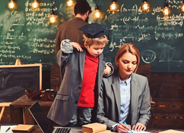 El chico genio enseña a mujeres y hombres en pizarra. Hijo con madre y padre tienen lección. Pequeño niño y familia en el aula. Disfruta del día escolar. Formación y desarrollo — Foto de Stock