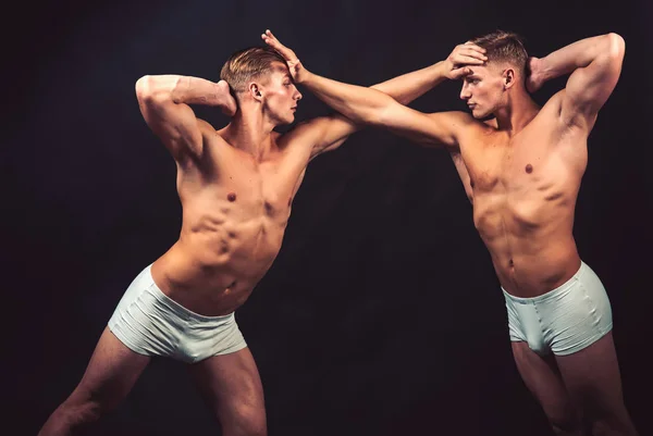 La amistad de los hombres hace gimnasia. Gemelos hombres con cuerpo muscular en pose de equilibrio. Dieta fitness y flexibilidad en acrobacias. Gimnastas de circo en pilates o entrenamientos de yoga. Entrenamiento deportivo para culturista — Foto de Stock