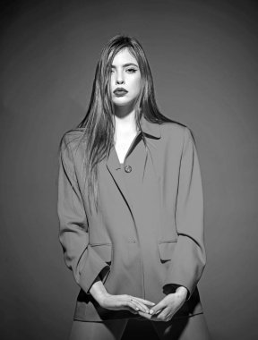 Şık makyaj ve uzun saç toplam kırmızı kıyafetiyle poz olan kadın. Moda kavramı. Lady koyu dudaklar kameraya bakıyor. Kız kırmızı resmi ceket, kırmızı arka planda gizemli yüz.