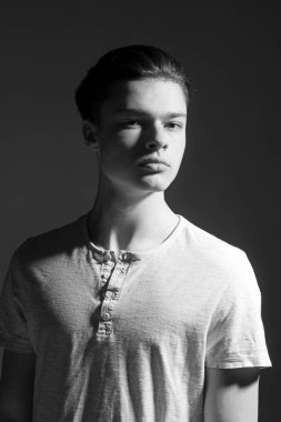 Maço şık uzun saç kesimi ile. Erkeklik kavramı. Pürüzsüz bir cilt ve yüz, kopya alanı üzerinde gölgeler olan adam. Adam kendine güvenen yüzüne ışık gömlek, siyah arka plan üzerinde.