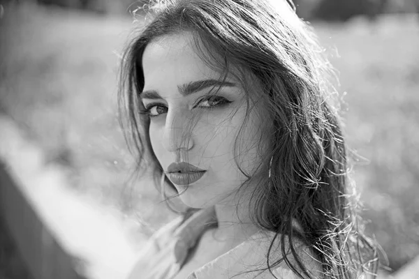 Kadın sakin yüz makyaj ile arka plan, doğa defocused. Uzun saçlı kız güneşli günde açılarak gömlek giyer. Bayan çekici görünüyor, yakın çekim. Cazibe kavramı.