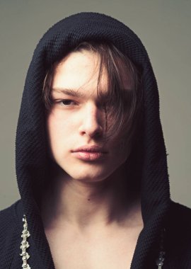 Siyah hood, gri arka planda emin yüz adam. Maço siyah bornoz ile kukuleta, yakın çekim. Erkeklik kavramı. Pürüzsüz cilt yüz ve boyun kameraya bakarak üzerinde olan adam.