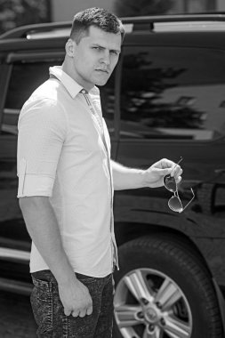 Sürücü hazır yakınındaki şehir sokak araba. Şık giysiler açık güneşli üzerinde iş adamı. Otomobil taşıma adam. Seyahat ve ulaşım kavramı