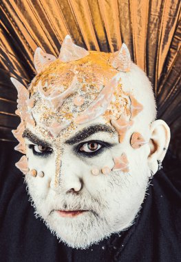 Dikenler veya siğiller, baş yüz pırıltılar ile kaplı, yakın çekim. Uzaylı, iblis büyücü makyaj. Sakallı canavar makyaj ile komuta sizde. İblis altın yaka, siyah arka plan ile. Fantezi kavramı.