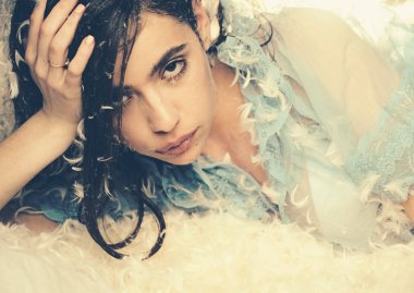 İhale pijama rahatlatıcı uzun saçlı kadın. Kız sakin yüzünde tüyler ve kabartmak ile kaplı yatakta yatıyordu. Yumuşak ve nazik bir kavram. Şeffaf mavi geceliği Bayan yatakta yatıyordu, yakın çekim.