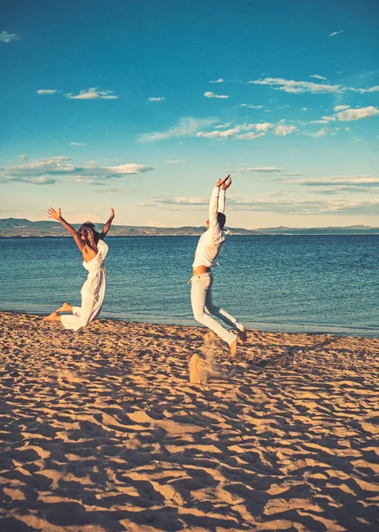 Mariage sur la plage tropicale avec couple heureux sautant sur le sable . — Photo