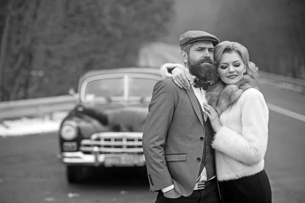 Brutal barbudo homem com um inteligente bigode morena abraçar mulher no carro retro estilo . — Fotografia de Stock