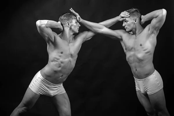 Vriendschap van mannen doen gymnastiek. Twins mannen met gespierd lichaam in evenwicht vormen. Fitness dieet en flexibiliteit acrobatiek. Circus gymnasten op pilates of yoga opleiding. Sport training voor bodybuilder — Stockfoto