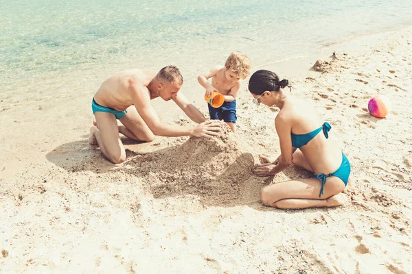 Family travel with kid on mothers or fathers day. Love and trust as family values. Summer vacation of happy family. Mother and father with son make sand castle on beach. Child with father and mother.