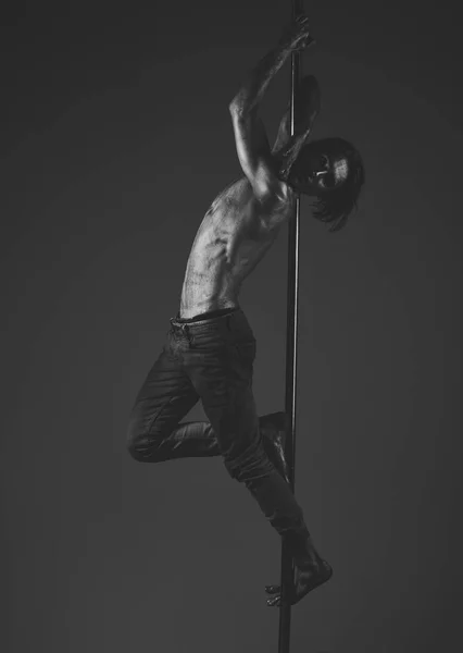 Um tipo pendurado num poste de metal. Atleta, esportista realizando pole dance — Fotografia de Stock