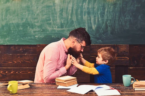 Profesor dando explicaciones a un niño pequeño. Tutor y su pequeño estudiante tienen una conversación sobre el comportamiento. Hombre de camisa rosa y chico rubio vista lateral en clase — Foto de Stock