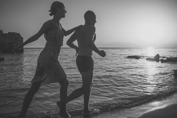 Silhouette de couple sensuel marcher sur la plage avec coucher de soleil au-dessus de la surface de la mer sur fond. Couple amoureux sur rendez-vous romantique en soirée au bord de la mer. Romance et concept d'amour . — Photo