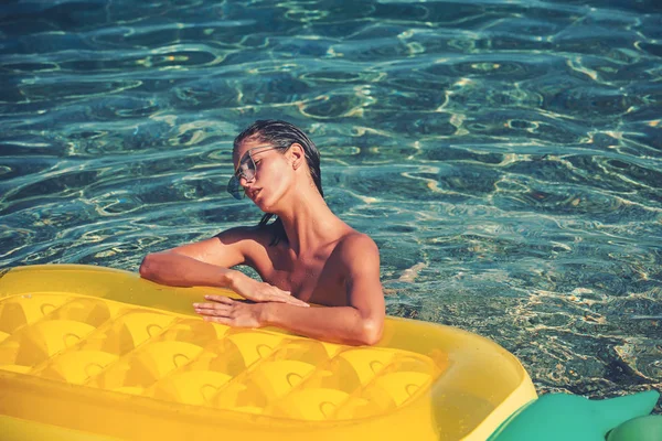 Vacances d'été et voyage à l'océan. plage d'été avec femme sexy bronzer au matelas d'air d'ananas jaune — Photo