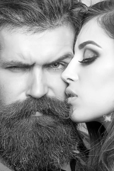 La mujer sensual besa al hombre barbudo, amor. Mujer con piel de maquillaje e hipster con barba larga. Pareja en el amor y el concepto familiar. Salón de belleza y peluquería. Concepto de cuidado de la piel y el cabello —  Fotos de Stock