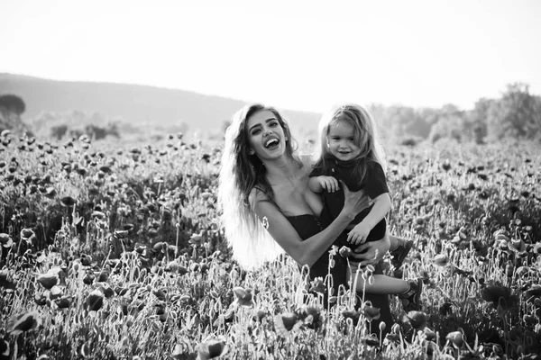 Fête des mères, fille et petit garçon dans le champ de pavot — Photo