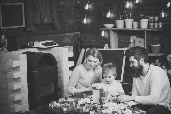 A família passa o tempo juntos na sala de jogos. O miúdo com pais brinca com blocos de plástico. Pai, mãe e filho bonito jogar com tijolos construtor — Fotografia de Stock