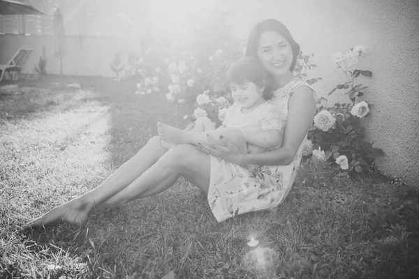 Máma a dítě se usmívá na rozkvetlé květy růže — Stock fotografie