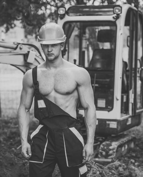 Constructor muscular en sombrero duro lleva overoles . —  Fotos de Stock