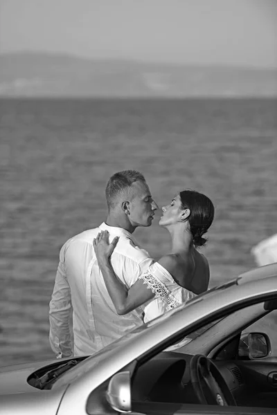 Familia y día de San Valentín. Mujer sexy y hombre en el mar cerca del coche. Las relaciones de amor de la pareja disfrutando del día de verano juntos. Pareja en el amor relajarse después del viaje por carretera. Vacaciones de verano y viajes — Foto de Stock