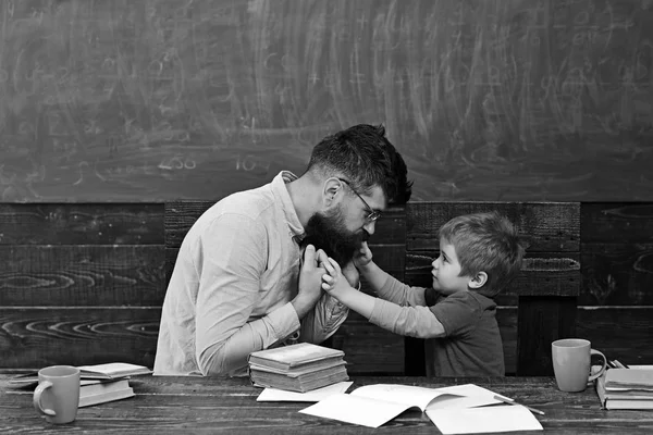 Insegnante di sesso maschile che dà spiegazioni ai bambini piccoli. Tutor e il suo piccolo studente hanno una conversazione sul comportamento. Uomo in camicia rosa e biondo ragazzo vista laterale in aula — Foto Stock