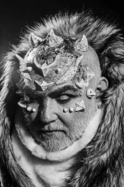 Senior man with white beard dressed like monster. Alien, demon, sorcerer makeup. Dark arts concept. Man with thorns or warts in fur coat. Demon on black background, close up. — Stock Photo, Image