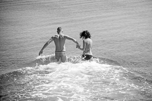 Feliz joven pareja divirtiéndose, hombre y mujer en el mar en la playa . — Foto de Stock