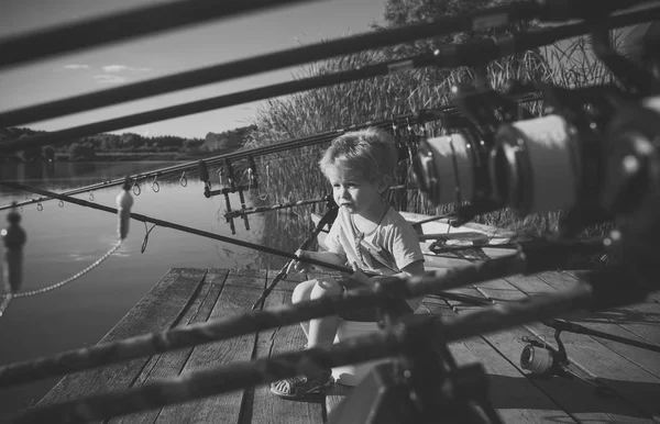 Pequeño niño pescando en la orilla del río con caña de pescar —  Fotos de Stock