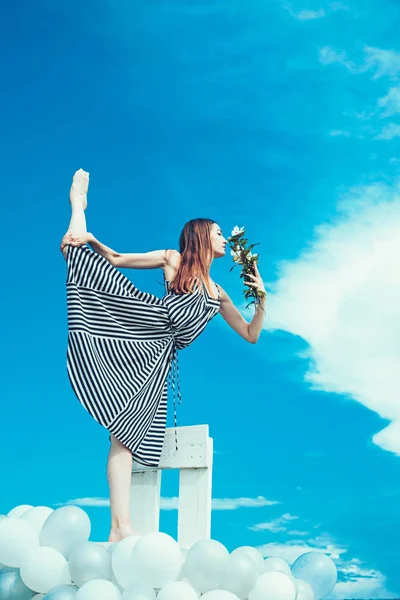 Μόδα Πορτρέτο γυναίκας. το κορίτσι με τα λουλούδια κάθονται στον ουρανό. αίσθημα ελευθερίας και όνειρα. έμπνευση και φαντασία. γυναίκα στο καλοκαιρινό φόρεμα με μπαλόνια κόμμα. ακροβατικά και τον αθλητισμό. SPLI — Φωτογραφία Αρχείου
