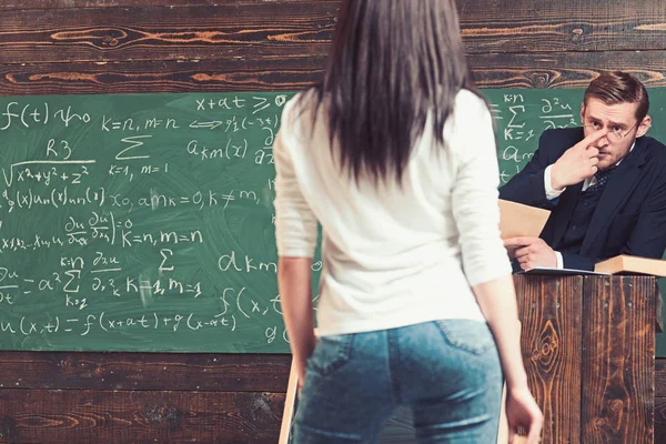 数学の教授は彼の若い美しい女性学生を見つめてします。教室で緑のボードの前に立って素敵なお尻と女の子を元に戻す — ストック写真
