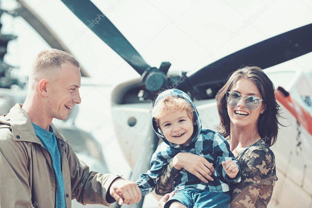 Around the world. Mother and father with son at helicopter. Family vacation. Family couple with boy child on vacation trip. Helicopter tour and travel. Air travel. Enjoying travelling by air