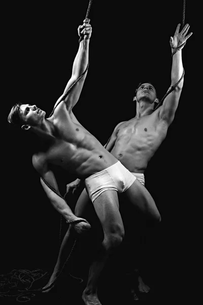 Дружба чоловіків робить гімнастику. Близнюки чоловіки з м'язистим тілом на мотузці. Циркові гімнастки на пілатесах або тренуваннях з йоги. Фітнес-дієта і гнучкість в акробатиці. Спортивні тренування для культуристів . — стокове фото