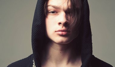 Erkeklik kavramı. Maço siyah bornoz ile kukuleta, yakın çekim. Siyah hood, gri arka planda emin yüz adam. Pürüzsüz cilt yüz ve boyun kameraya bakarak üzerinde olan adam