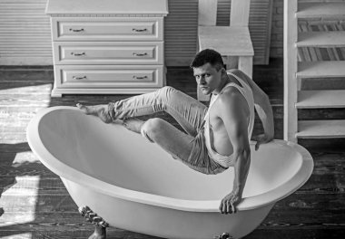 Banyo adam otur. Adam banyoda. Seksi maço kolsuz bluz ve kot moda. Fitness modeli güçlü beden sağlığı ile. Hijyen ve banyo kavramı