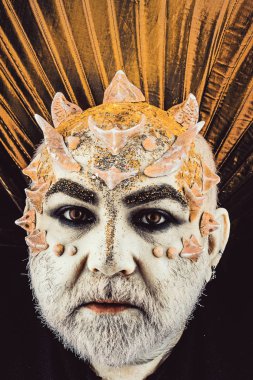 Dikenler veya siğiller, baş yüz pırıltılar ile kaplı, yakın çekim. İblis altın yaka, siyah arka plan ile. Uzaylı, iblis büyücü makyaj. Fantezi kavramı. Sakallı canavar makyaj ile üst düzey adam