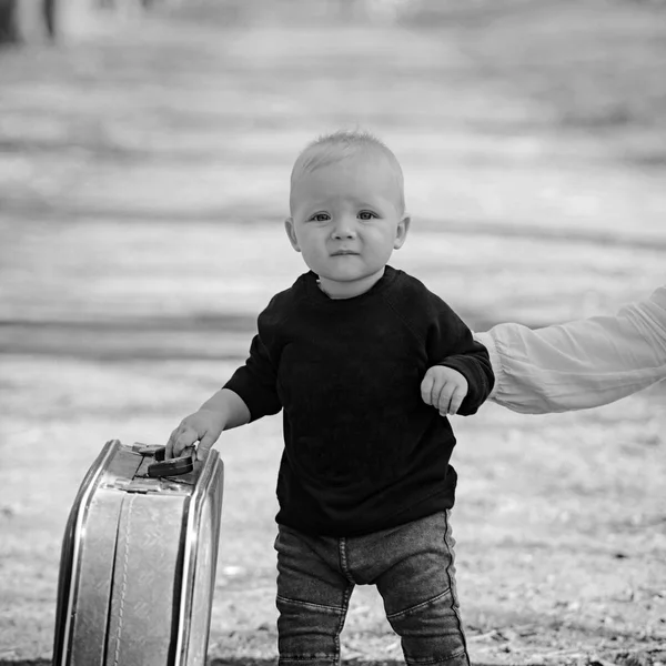 Small boy carry retro suitcase on natural landscape. Child travel for vacation with bag with mothers hand. Kid traveler with luggage outdoor. Vacation traveling and wanderlust