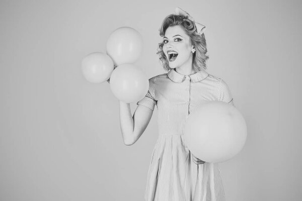 pinup vintage girl on a grey room with balloons.