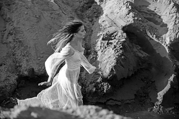 Woman in white dress in canyon on sunny day, fashion