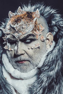 Siyah arka plan, cehennemdeki şeytanlar kapatın. Karanlık sanatlara kavramı. Beyaz sakallı komuta sizde canavar gibi giyinmiş. Dikenler veya siğiller kürk paltolu adam. Uzaylı, iblis, büyücü makyaj