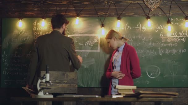 Bellissimi giovani studenti di fronte alla grande lavagna. Tutor aiutare la sua giovane studentessa con la matematica. Concetto di istruzione privata. Compagno di classe Educare Amico Conoscenza Lezione Concetto. Insegnante e studente — Video Stock