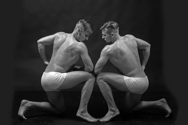 Circus gymnasten op pilates of yoga opleiding. Vriendschap van mannen doen gymnastiek. Fitness dieet en flexibiliteit acrobatiek. Sport training voor de bodybuilder. Twins mannen met gespierd lichaam in pose — Stockfoto