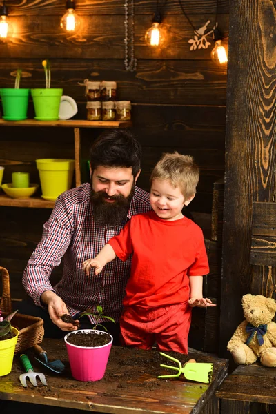 Flower care watering. Soil fertilizers. Father and son. Fathers day. Family day. Greenhouse. happy gardeners with spring flowers. bearded man and little boy child love nature. Involved in work