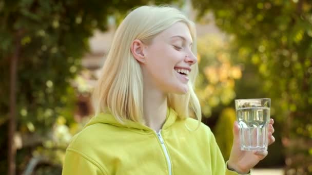 Portrait de femme avec de l'eau en verre. Une jeune femme qui boit de l'eau. Clouse up portrait de fille blonde . — Video