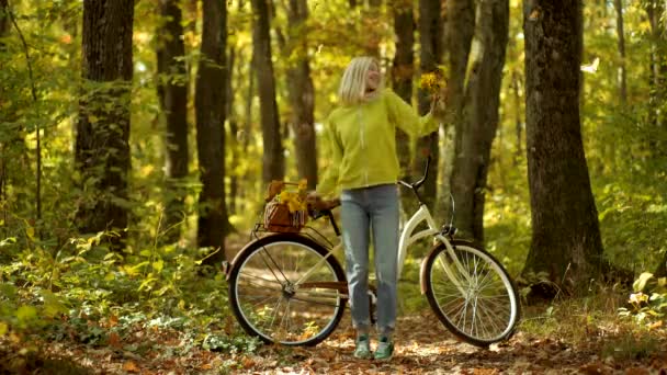 秋天的女人在秋天公园与绿色套头衫。户外大气时尚照片的年轻美丽的女士在秋天的风景。带秋叶的欢快的年轻女子的肖像. — 图库视频影像
