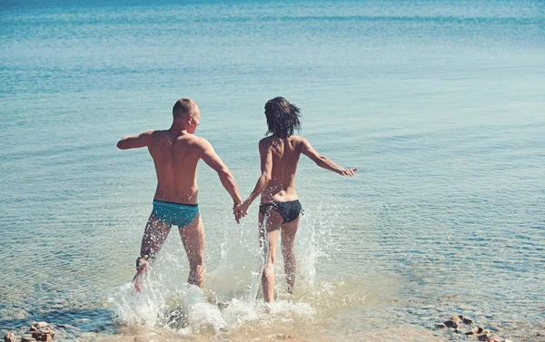 Femme sexy et l'homme va nager dans l'eau de mer. femme sexy et homme courir pour la natation . — Photo