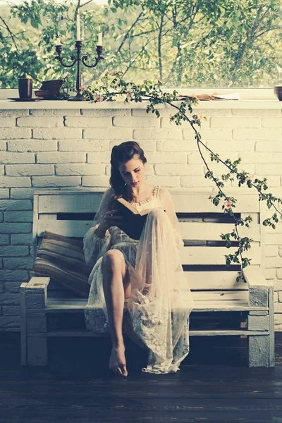 Czytanie książki na drewnianej ławce. czytanie z młoda kobieta w białej sukni. — Zdjęcie stockowe