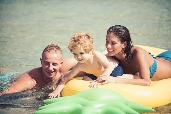 父とマットレスに近い母は、息子と一緒に泳ぐ。家族は、一緒に時間を過ごす楽しんでいます。エアマットレス パイナップル両親と海の形をしたかわいい子少年が座っています。家族での休暇の概念 — ストック写真